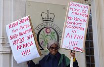 Una manifestante muestra un par de carteles con consignas, ante la sede del Tribunal Supremo del Reino Unido, en Londres.