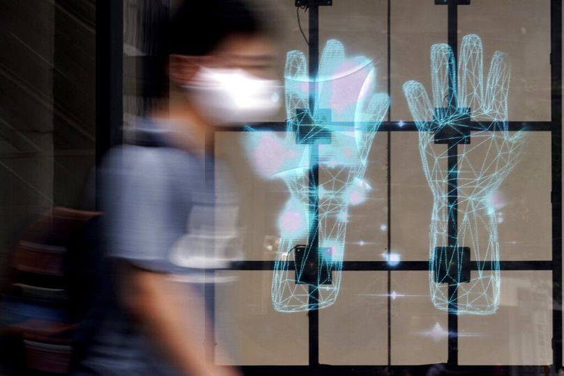 A man wearing a face mask against the spread of the new coronavirus walks past a public notice to wash hands in Tokyo, July 2020