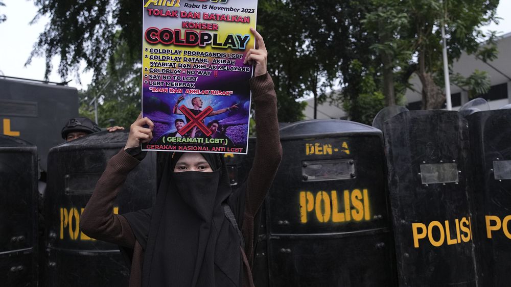 Жена държи плакат по време на митинг срещу британската група