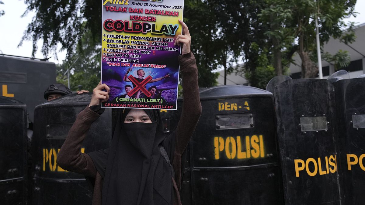 Eine Frau hält ein Plakat während einer Demonstration gegen die britische Band Coldplay vor ihrem Konzert in Jakarta, Indonesien