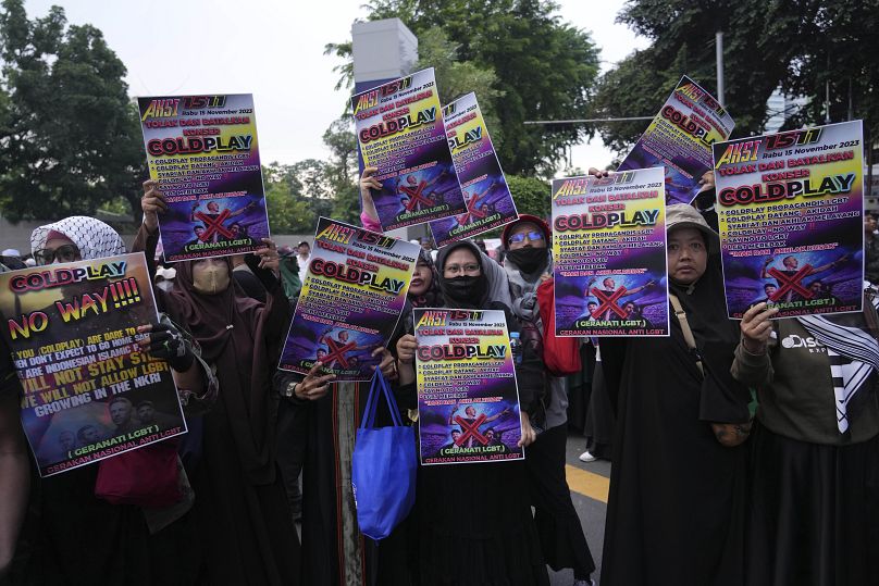 Des femmes musulmanes tiennent des affiches lors d'un rassemblement contre le groupe britannique Coldplay avant son concert à Jakarta, en Indonésie