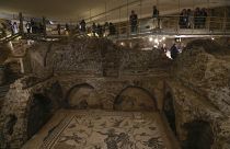 Journalists visit an ancient necropolis along the via triumphalis, an archaeological area containing a Roman burial ground .