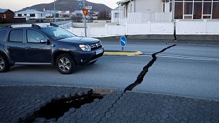 A car drives toward a fissure in a road in the town of Grindavik, Iceland Monday Nov. 13, 2023 following seismic activity. 