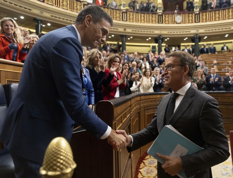 Spain's acting Prime Minister Pedro Sanchez, left, shakes hands with conservative opposition leader Alberto Nunez Feijoo.