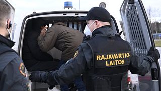 Guardias fronterizos colocan a solicitantes de asilo que habían cruzado desde Rusia en una furgoneta para ser transportados a un centro de acogida, cerca de Lappeenranta Finlandia, 16 de noviembre de 2023