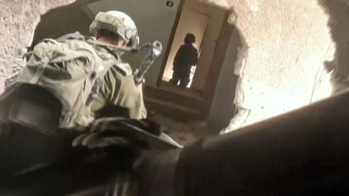 In this image taken from video released by Israeli Defense Forces, Thursday, Nov 16, 2023, Israeli soldiers wind their way through a hole in a building in Gaza