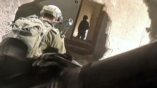 In this image taken from video released by Israeli Defense Forces, Thursday, Nov 16, 2023, Israeli soldiers wind their way through a hole in a building in Gaza