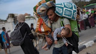 أب نازح يحمل طفله في مخيم البريج بقطاع غزة