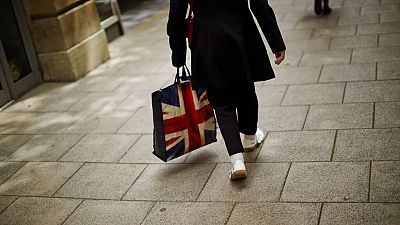 In this Tuesday, July 5, 2016 photo, a woman carrying a bag decorated with a Great Britain's union flag, walks a long a street in downtown Peterborough, East of England.