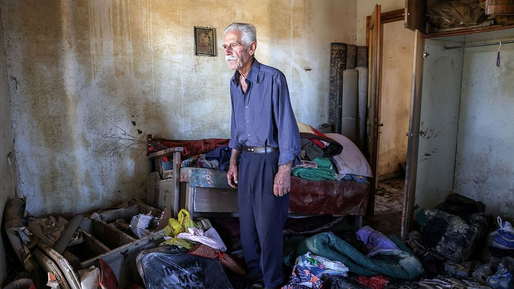 Василис Цацарелис, 80, стои сред отломки в повредената си къща