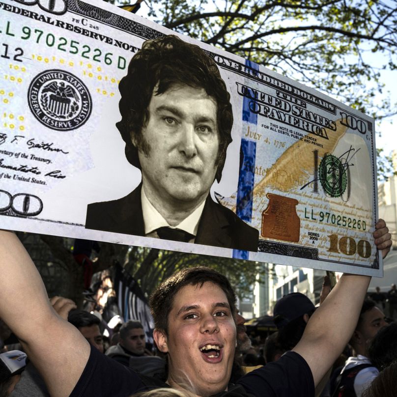 Agustín Salem sostiene un billete de dólar estadounidense de gran tamaño con la cara del candidato presidencial Javier Milei, el 25 de septiembre.