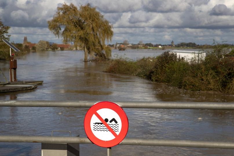 This general view from a bridge with a 'no swimming' sign shows fields inundated by floodwaters at Poperinge, West Flanders on November 11, 2023