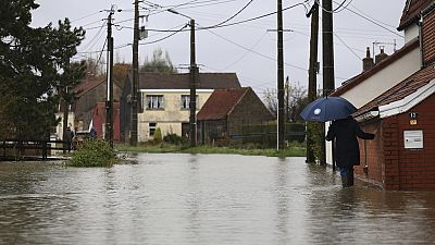 A woman walks in a flooded street of Le Doulac, northern France, Tuesday, Nov. 14, 2023. 