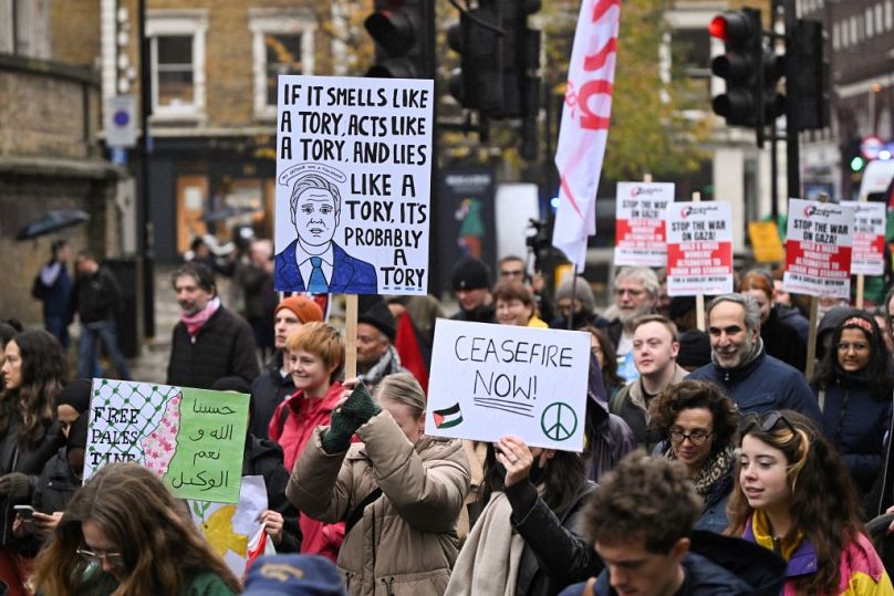 Protesters hold placards with messages for Britain's Labour leader Keir Starmer as they walk past his office during the 'Day of Action for Palestine'