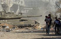 На кадрах видеозаписи AFPTV видно, как израильский бронетранспортёр проезжает мимо палестинцев, покидающих город Газа пешком на фоне продолжающихся боёв, 18 ноября 2023 года.