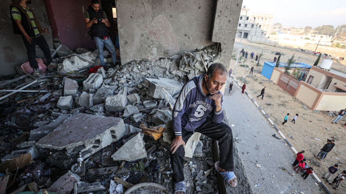 A Palestinian man cries, looks at the destruction after Israeli fighter jets strike residential buildings in Hamad Town, northwest of Khan Yunis, Gaza