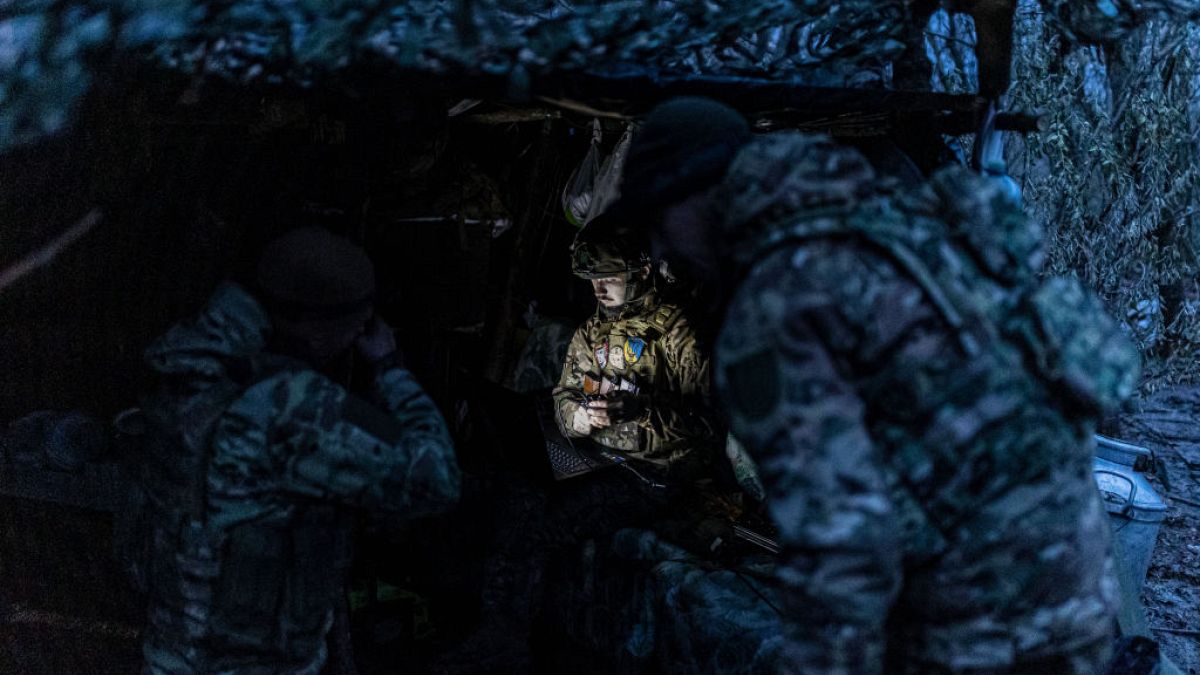 A Ukrainian soldier works with a computer next to a shelter in his fighting position in the direction of Bakhmut, Ukraine
