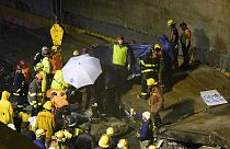Equipos de rescate transportan el cuerpo de uno de los fallecidos en el colapso de un paso a nivel en Santo Domingo el sábado 18 de noviembre