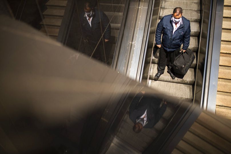 A man takes an escalator to enter Schuman train and metro station in Brussels, July 2020