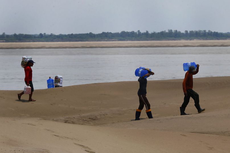 Residents of a riverside community in Amazonas state carry food and containers of drinking water distributed due to drought and high temperatures.