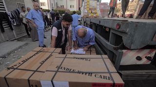  طاقم طبي فلسطيني يفرغ صناديق أدوية من شاحنة وصلت إلى مجمع الناصر الطبي، خان يونس قطاع غزة.
