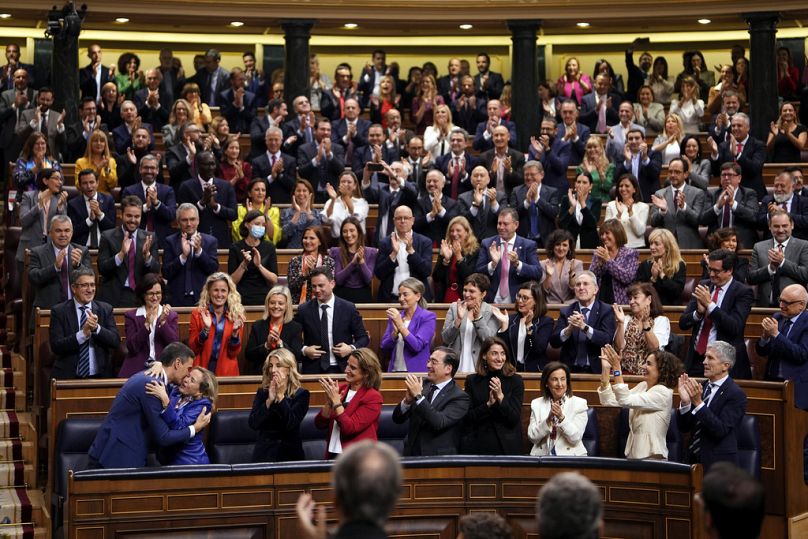 Spain's reelected Prime Minister Pedro Sanchez, bottom left, embraces Economy Minister and first Deputy Prime Minister Nadia Calvino at the Spanish Parliament in Madrid, Spain