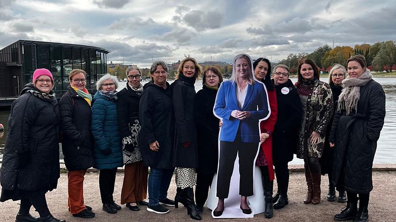 Social Democrat activists and politicians pose with a cardboard cut-out of Jutta Urpilainen, October 2023