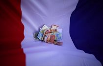 Bank notes lie on a French flag, April 7, 2022. 