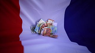 Bank notes lie on a French flag, April 7, 2022. 