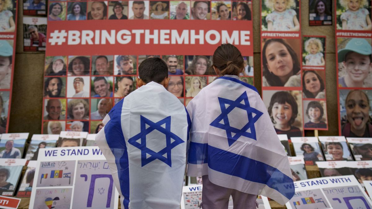 FILE - Children look at photographs of Israelis kidnapped by Hamas during a rally joined by hundreds in solidarity with Israel in Romania, 2023. 
