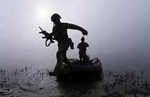 A Ukrainian serviceman jumps out of the boat on the shore of Dnipro river at the frontline near Kherson, Ukraine, Sunday Oct. 15, 2023.