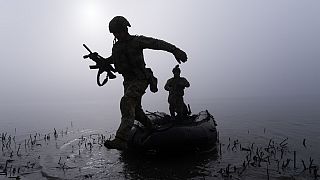 A Ukrainian serviceman jumps out of the boat on the shore of Dnipro river at the frontline near Kherson, Ukraine, Sunday Oct. 15, 2023.