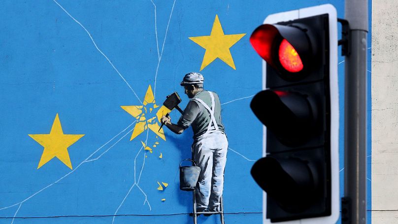 A view of the Banksy Brexit mural of a man chipping away at the EU flag in Dover, England