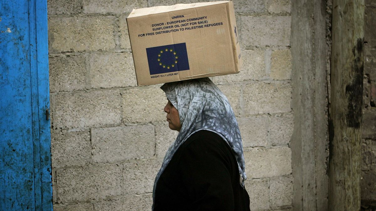 Egy palesztin nő az Európai Unió által adományozott készleteket tartalmazó dobozt visz a Gázai övezet északi részén lévő Dzsebalíja menekülttábor egyik raktárában.