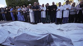 Palestinianos rezam pelos familiares mortos nos bombardeamentos israelitas, em frente à morgue do Hospital al Aqsa em Deir al Balah, na Faixa de Gaza