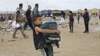 طفل فلسطيني يحمل زجاجات مياه سقطت من شاحنات المساعدات الإنسانية على الحدود مع مصر.