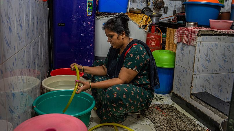 Aarti Sandeep Kawade fills buckets and pans with water for cooking and washing clothes and dishes inside her dwelling in Dharavi, one of Asia's largest slums, in Mumbai, India