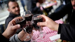 Customers toast with glasses of red wine in a restaurant outside Paris, France.