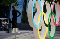 A mother watches her baby walking around near the Olympic rings installed outside the Japan Olympic Museum in Tokyo, Wednesday, Oct. 11, 2023.