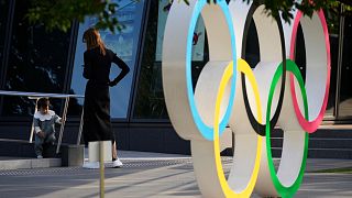 A mother watches her baby walking around near the Olympic rings installed outside the Japan Olympic Museum in Tokyo, Wednesday, Oct. 11, 2023.