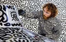 British artist Sam Cox, better known as Mr. Doodle, draws on a model spaceship for a live art performance at Central MTR Station in Hong Kong on November 19, 2023. 