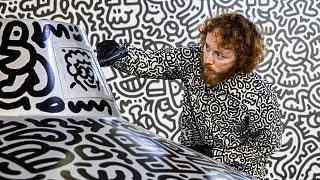 British artist Sam Cox, better known as Mr. Doodle, draws on a model spaceship for a live art performance at Central MTR Station in Hong Kong on November 19, 2023. 