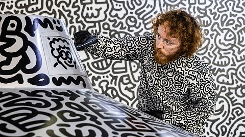 British artist Sam Cox, better known as Mr. Doodle, draws on a model spaceship for a live art performance at Central MTR Station in Hong Kong on November 19, 2023. 