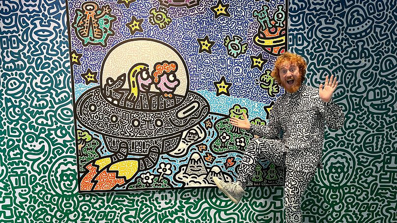 British artist Sam Cox, better known as Mr. Doodle, posing for a picture with his piece "The Doodles Leave Earth" at Pearl Lam Galleries in Hong Kong.
