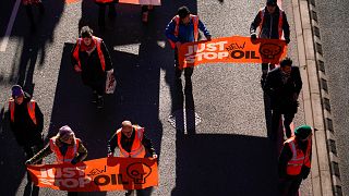  Активисти от групата Just Stop Oil държат транспаранти, до момента в който забавят трафик, маршируване по път във финансовия регион на Лондонското сити. 