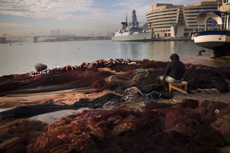 A fisherman repairs a net at the fishing port of Barcelona, June 2012