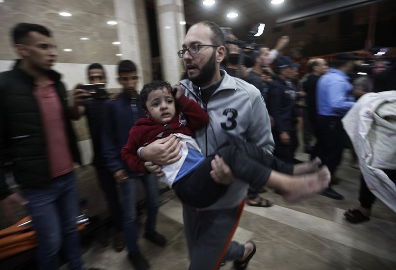 A wounded Palestinian child is carried into the Nasser Hospital following an Israeli bombardment on Khan Younis refugee camp, southern Gaza Strip, Tuesday, Nov. 21, 2023.