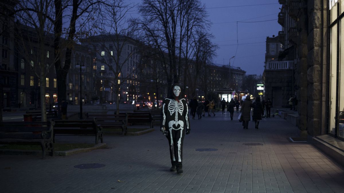 Eine Person in Skelett-Verkleidung läuft entlang einer Ladenzeile in Kiew, Ukraine. 21. November 2023.