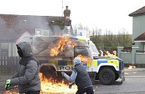 Imagen de dos ciudadanos enmascarados que han lanzado cócteles molotov a un vehículo de la policía británica, en Irlanda del Norte, el 10 de abril de 2023.