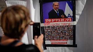 امرأة تصور معلقة تحمل صورة الرهائن الإسرائيلييين في غزة وصورة رئيس الوزراء الإسرائيلي وعبارة تطالبه بإعادتهم - تل أبيب. 2023/11/21
